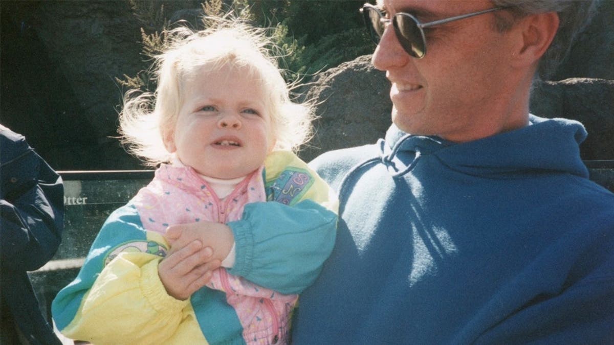 image shows father holding young daughter