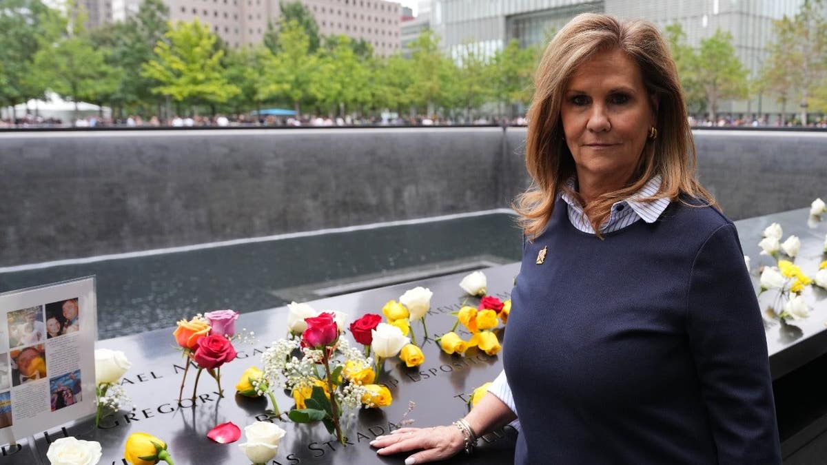 Terry Strada poses near her husband's name on the memorial