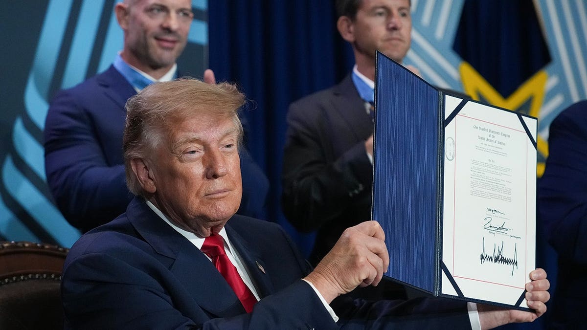 President Donald Trump holds up a signed document at the National Medal of Honor Museum in Arlington, Texas.